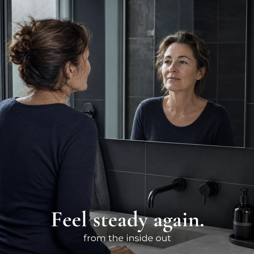Woman looking at herself in a mirror with text 'Feel steady again. from the inside out' in a bathroom setting.