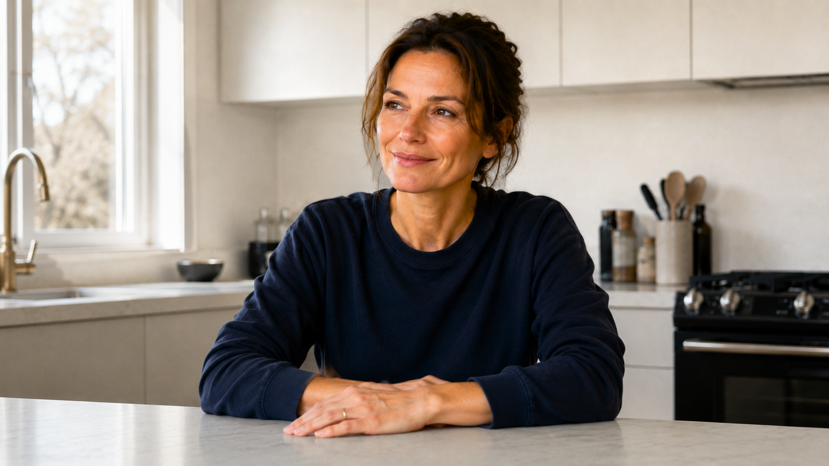Woman sitting at a kitchen counter with a neutral expression